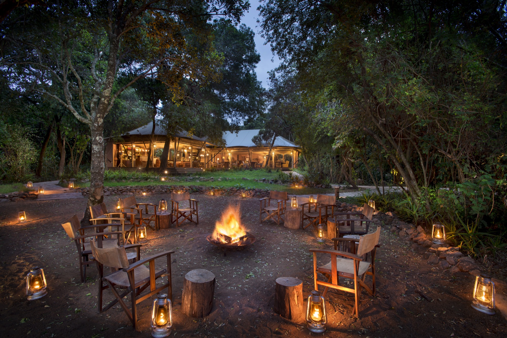 Boma fire with canvas chairs at &Beyond Bateleur Camp, South Camp, after dark