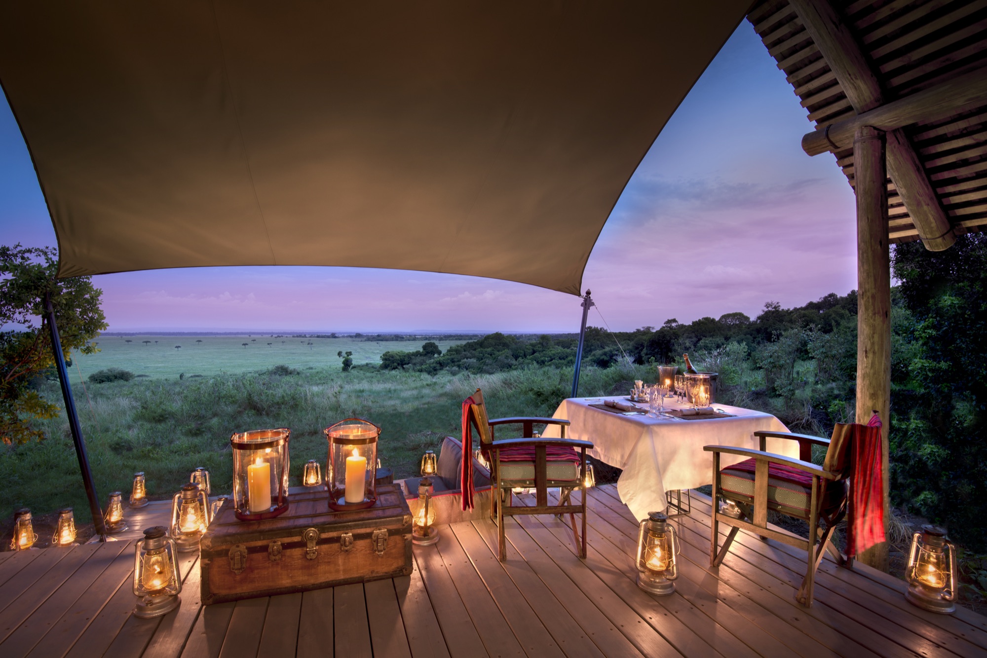 Dinner table on the deck under lanterns at &Beyond Bateleur Camp at dusk